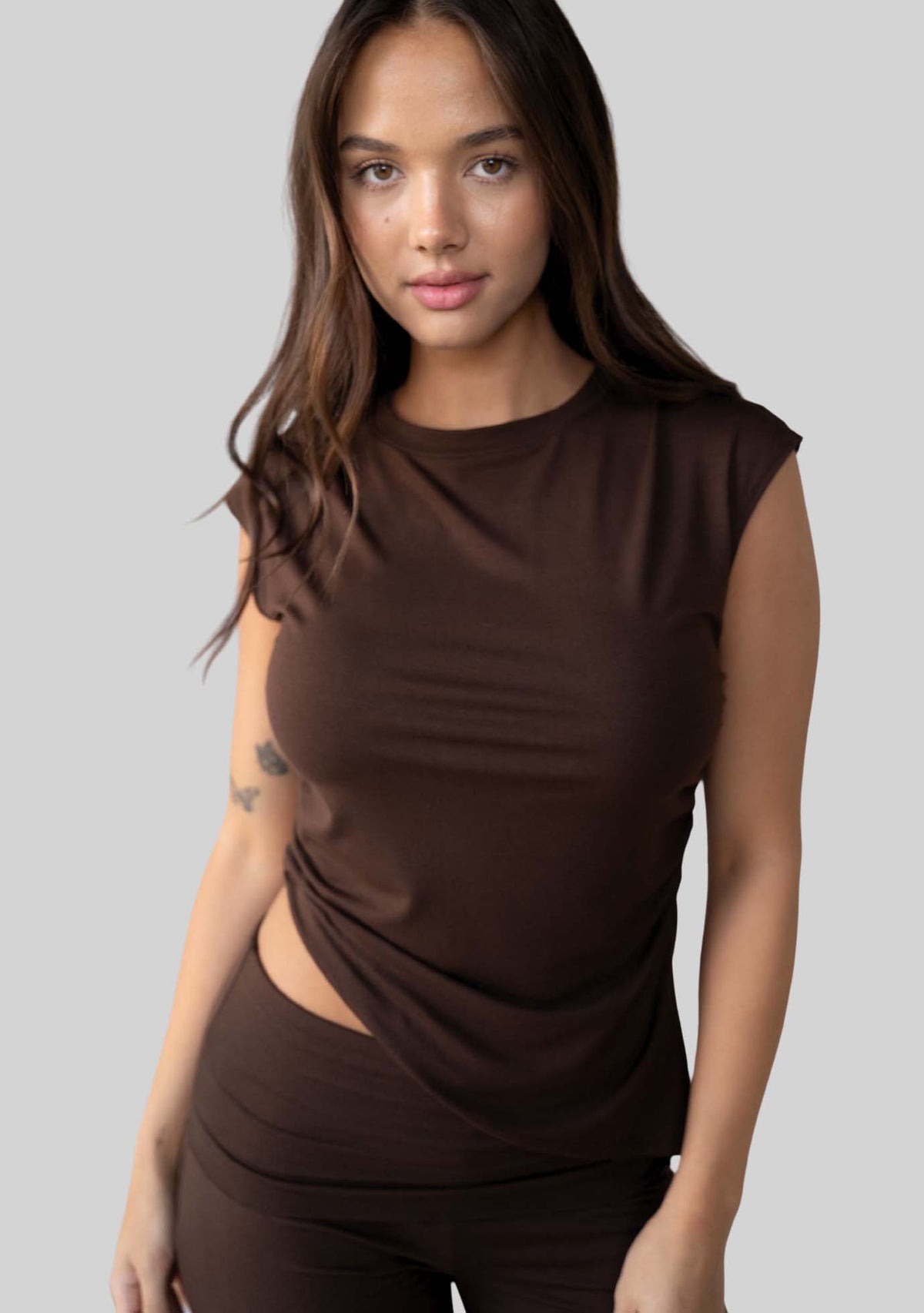 Model wearing the JALA Align Tee in Espresso with side shirring and an asymmetrical hem, front view