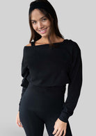 Model wearing the JALA Aela Top in Black, an off the shoulder long sleeve top, front view. [label] Leah is 5'7" XS