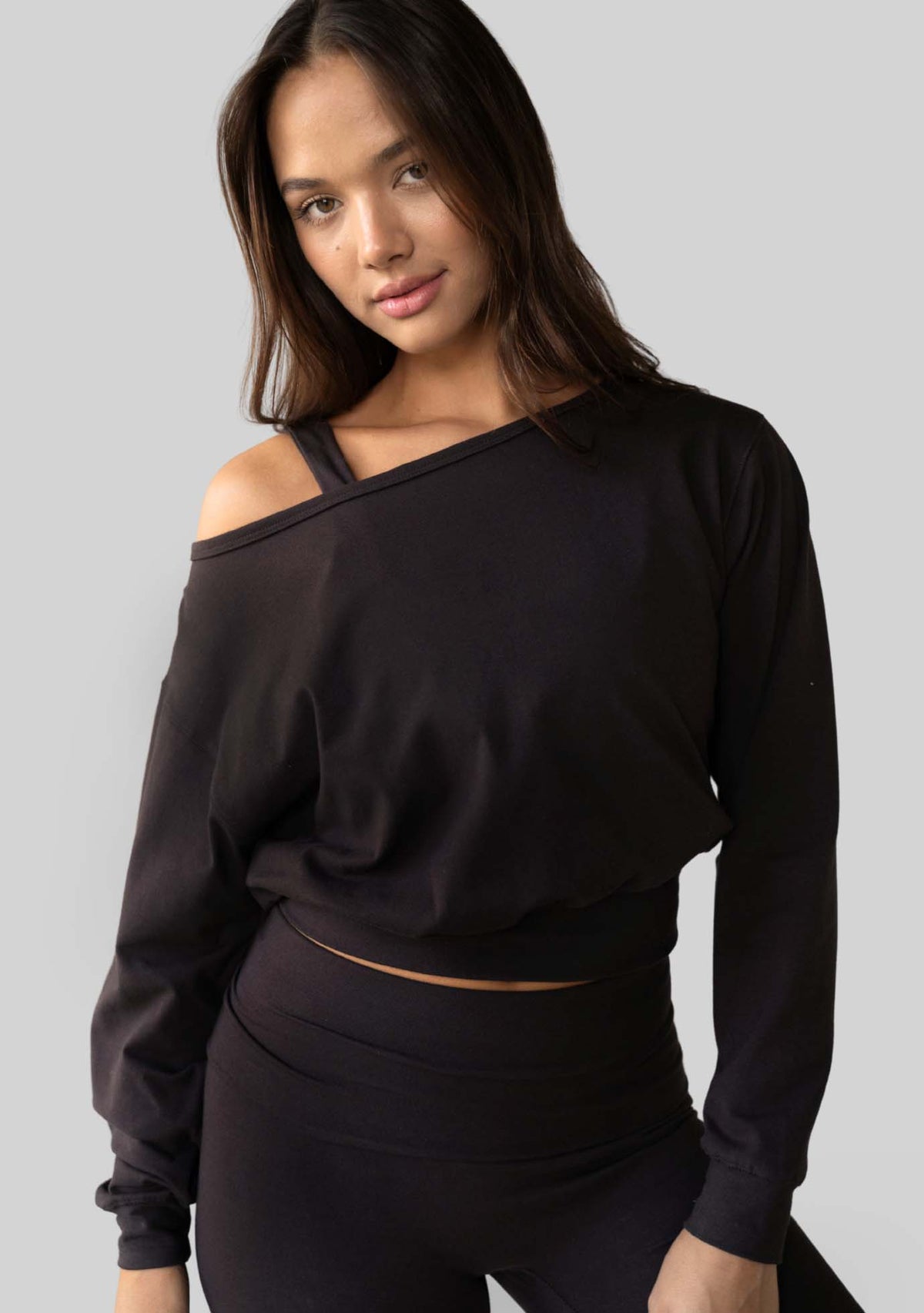 Model wearing the JALA Aela Top in Chocolate, an off the shoulder long sleeve top, front view. [label] Leah is 5'7" XS
