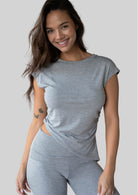 Model wearing the JALA Align Tee in Heather Grey with side shirring and an asymmetrical hem, front view