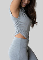 Side view of the JALA Align Tee in Heather Grey showing the side shirring