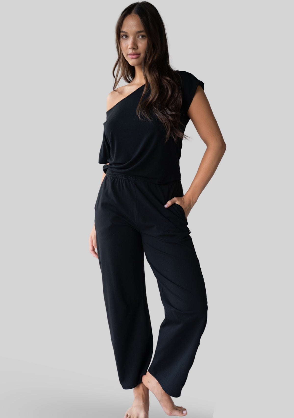 Model wearing the JALA Bliss Barrel Pant in Black, a relaxed barrel leg pant, front view. [label] Leah is 5'7" XS