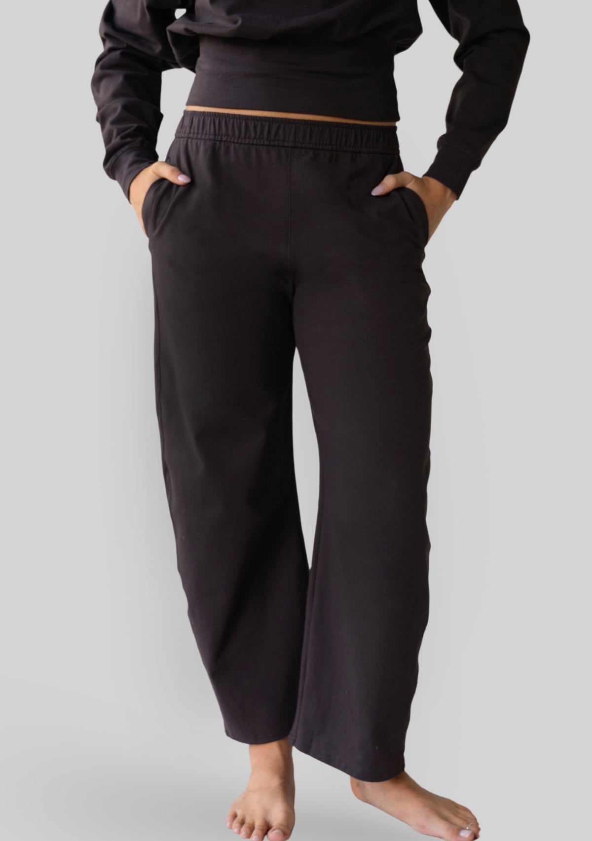 Model wearing the JALA Bliss Barrel Pant in Chocolate, a relaxed barrel leg pant with pockets, front view. [label] Leah is 5'7" XS