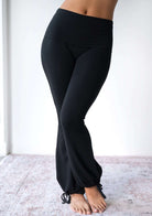 Model wearing the JALA Nama Balloon Flare Legging in Black with tie ankle balloon hem, front view. [label] Leah is 5'7" XS